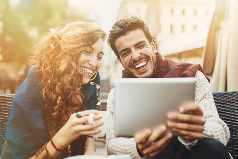 Couple laughing and looking at tablet