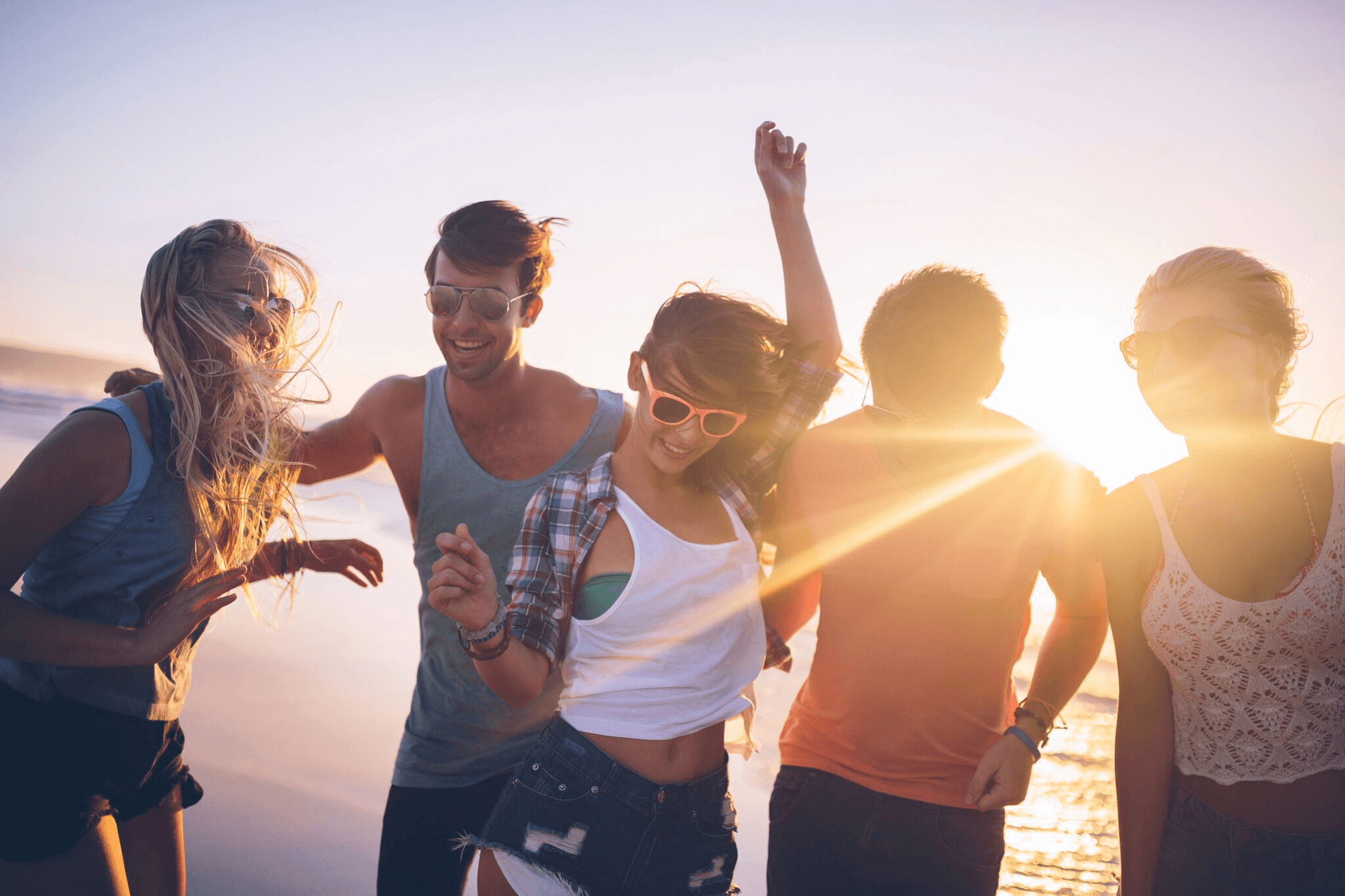 Group of happy friends on the beach at sunset