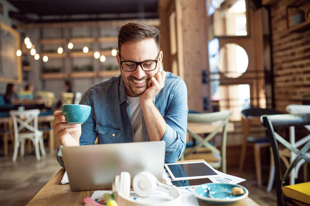 Making payments to Lottoland account Man drinking coffee and smiling at computer screen