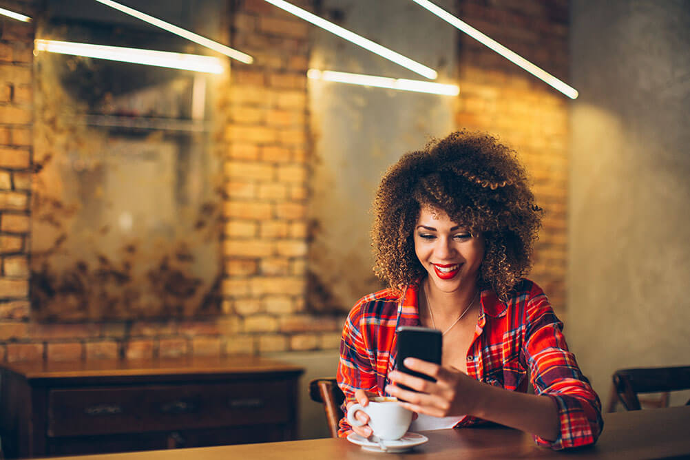 Woman smiling at her phone in a cafe