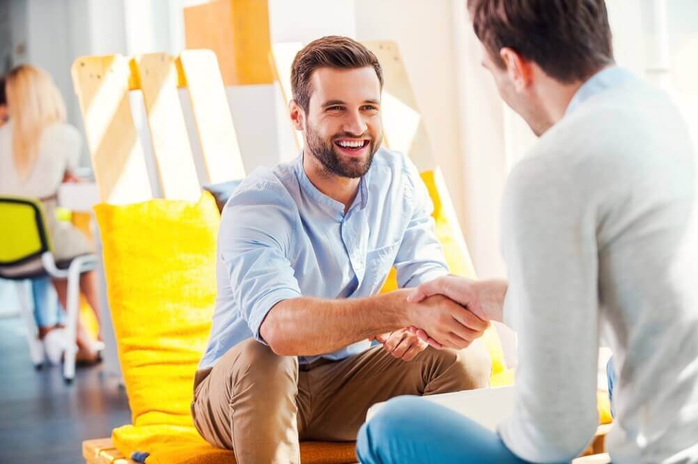 Two men smiling and shaking hands.