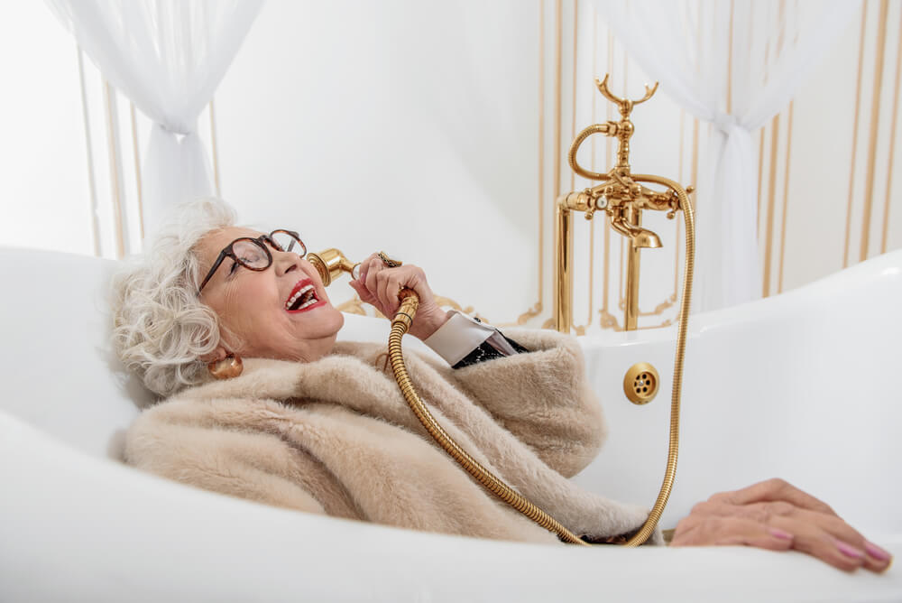 Old rich lady in a fur coat laughing while holding gold telephone