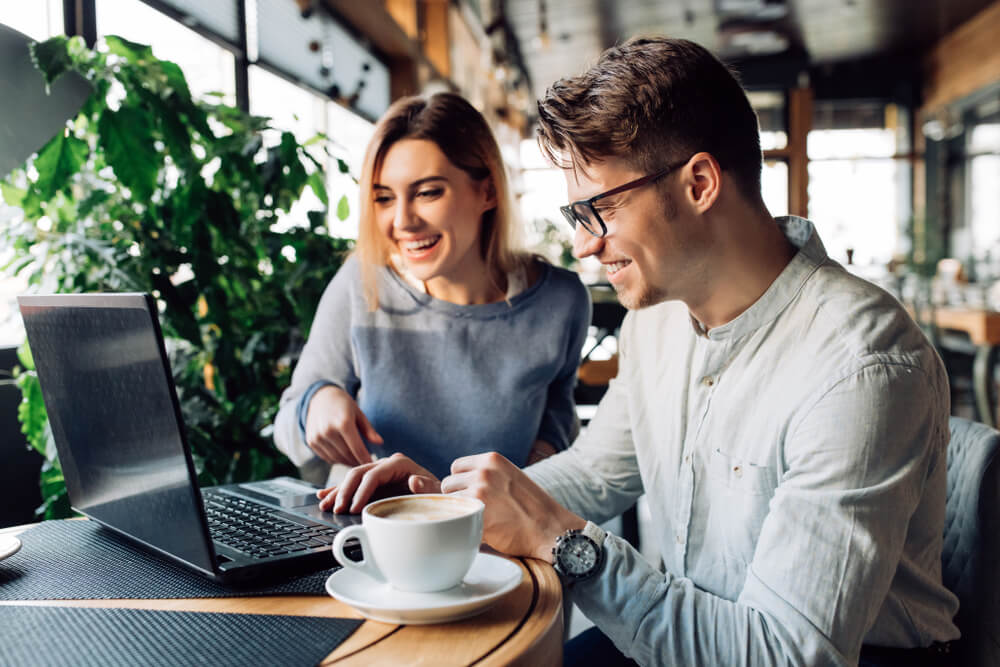 Irish couple betting on the Polish lottery online from their laptop at a cafe.