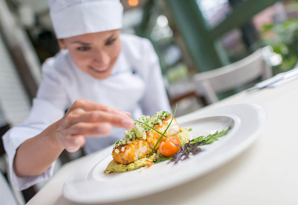 Smiling female chef prepares a dish at a Michelin star restaurant