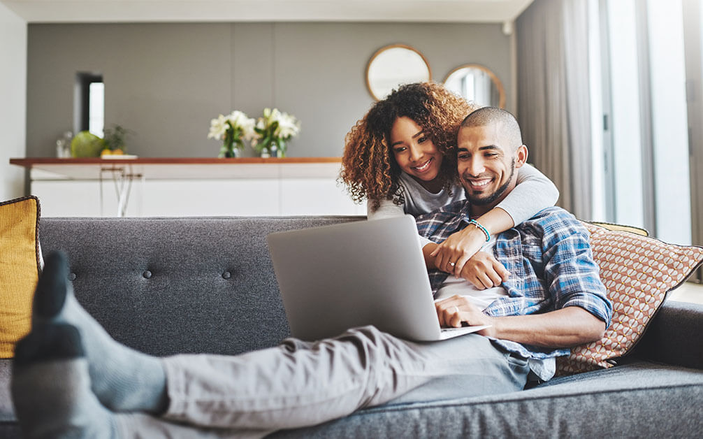 How to Play the Lottery online with Lottoland Couple celebrating a lottery win after checking results on a laptop