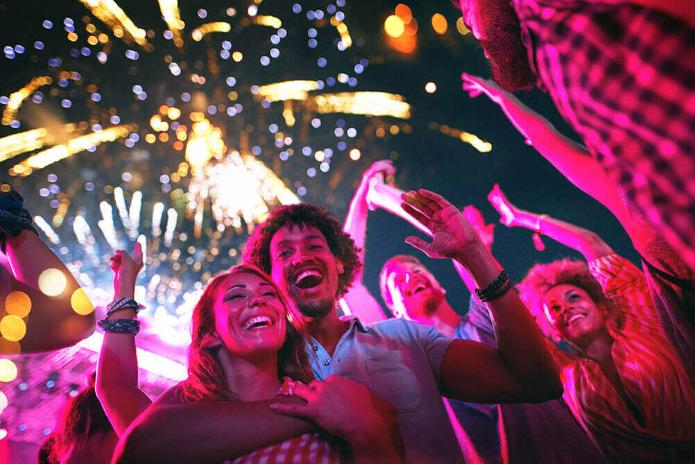 People celebrating on New Year's Eve with fireworks in the sky overhead