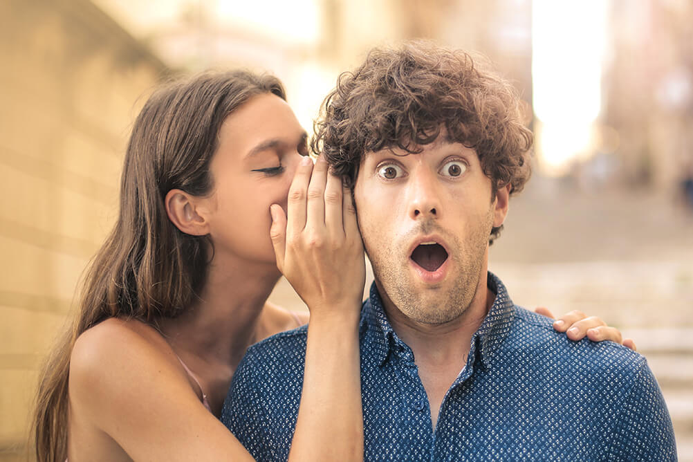 Woman whispering a secret into her boyfriend's ear