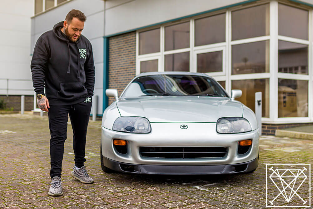 Jamie Balmer standing next to a Toyota Supra which looks like a millionaire car