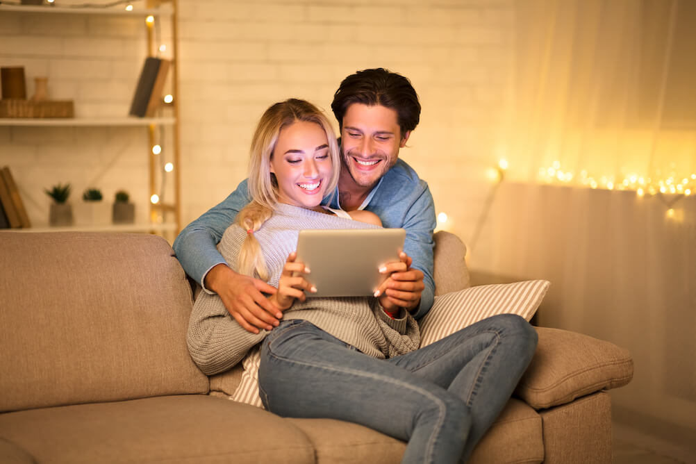 Hugging couple checking the lottery draw times on their iPad