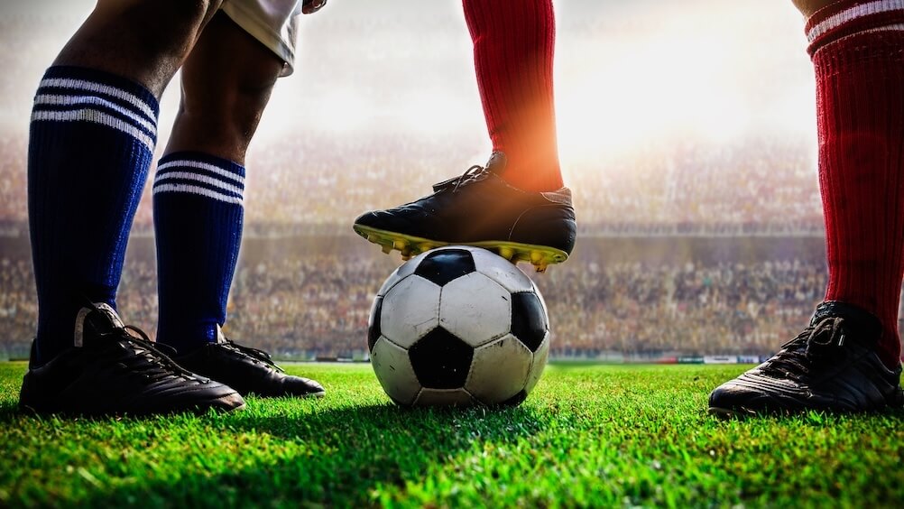 Draw No Bet Explained An image of the legs of two footballers on opposite teams, one with the ball beneath his foot. An equal match up is a good time to use draw no bet